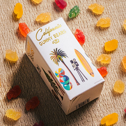 A box of CALI BEARS gummy bears with various fruit pieces displayed around it, set against a textured background.